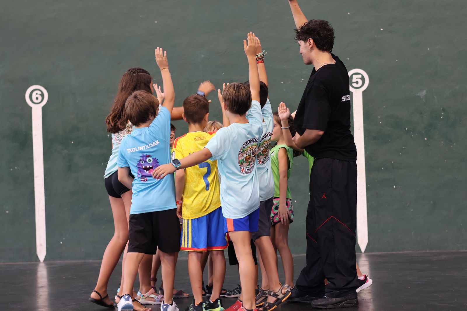 Niños y monitor de Space Breaking celebrando con las manos en alto al terminar un taller en Okondo