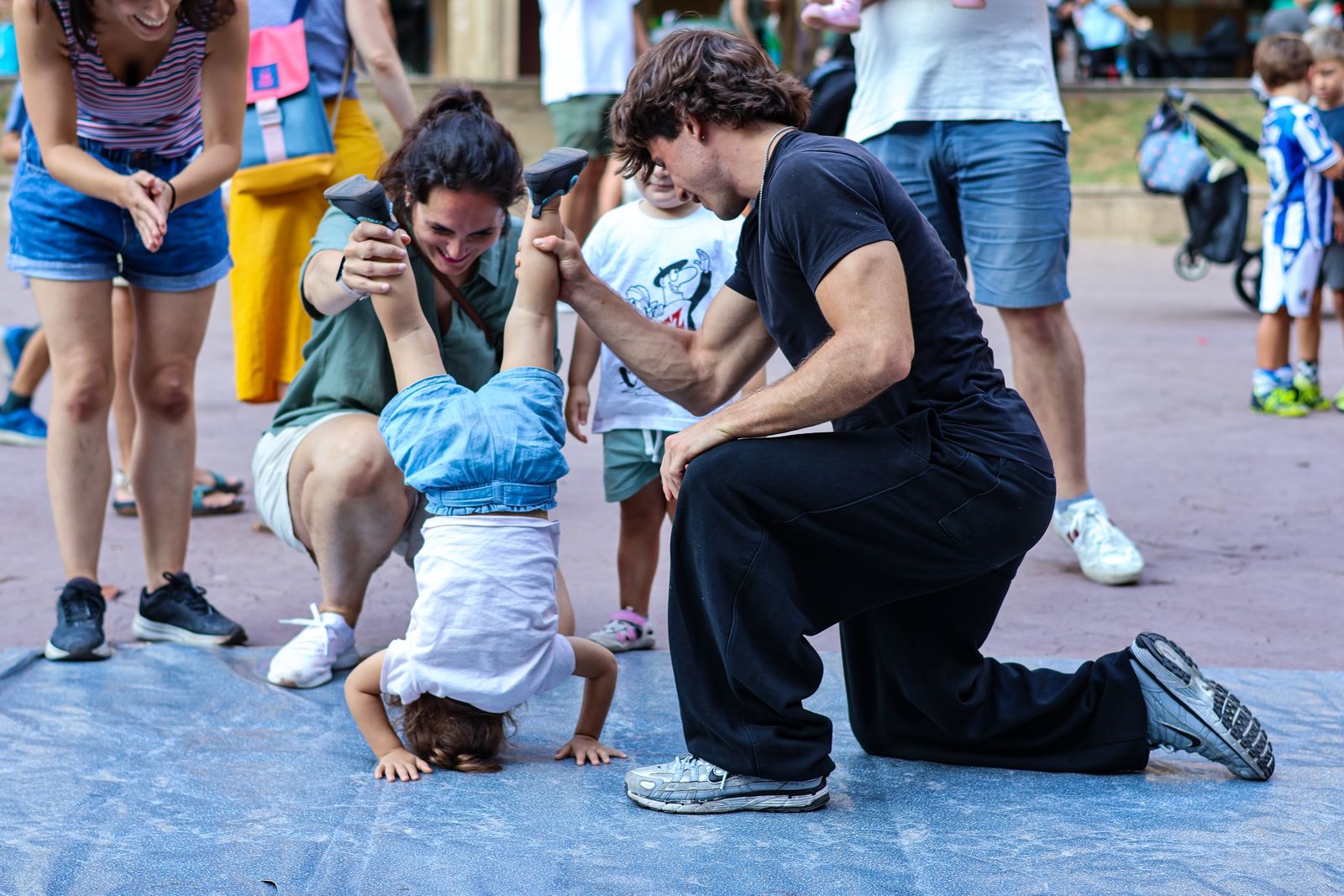 Monitores de Space Breaking ayudando a una niña pequeña a hacer el pino en un taller